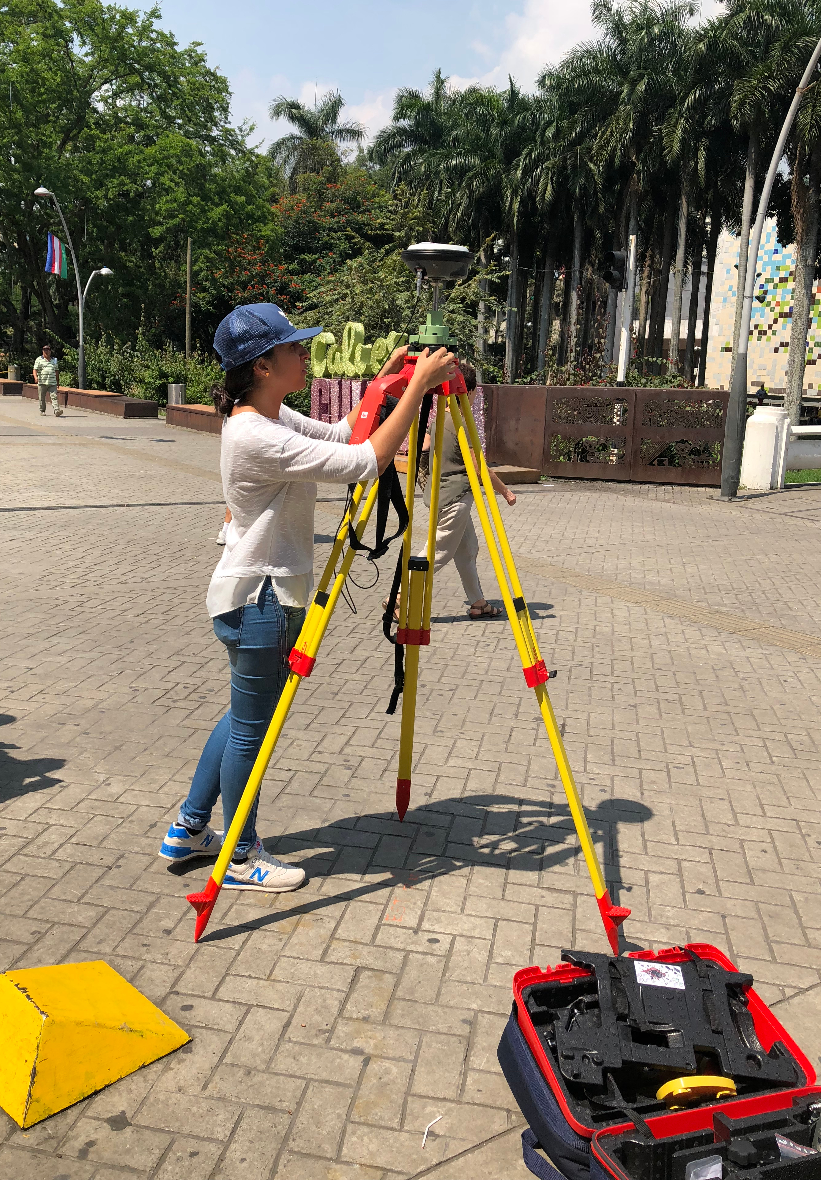 Mujer ubicada en el Bulevar del Río observando a través de un equipos receptor geodésico GNSS (Sistema Global de Navegación por Satélite)