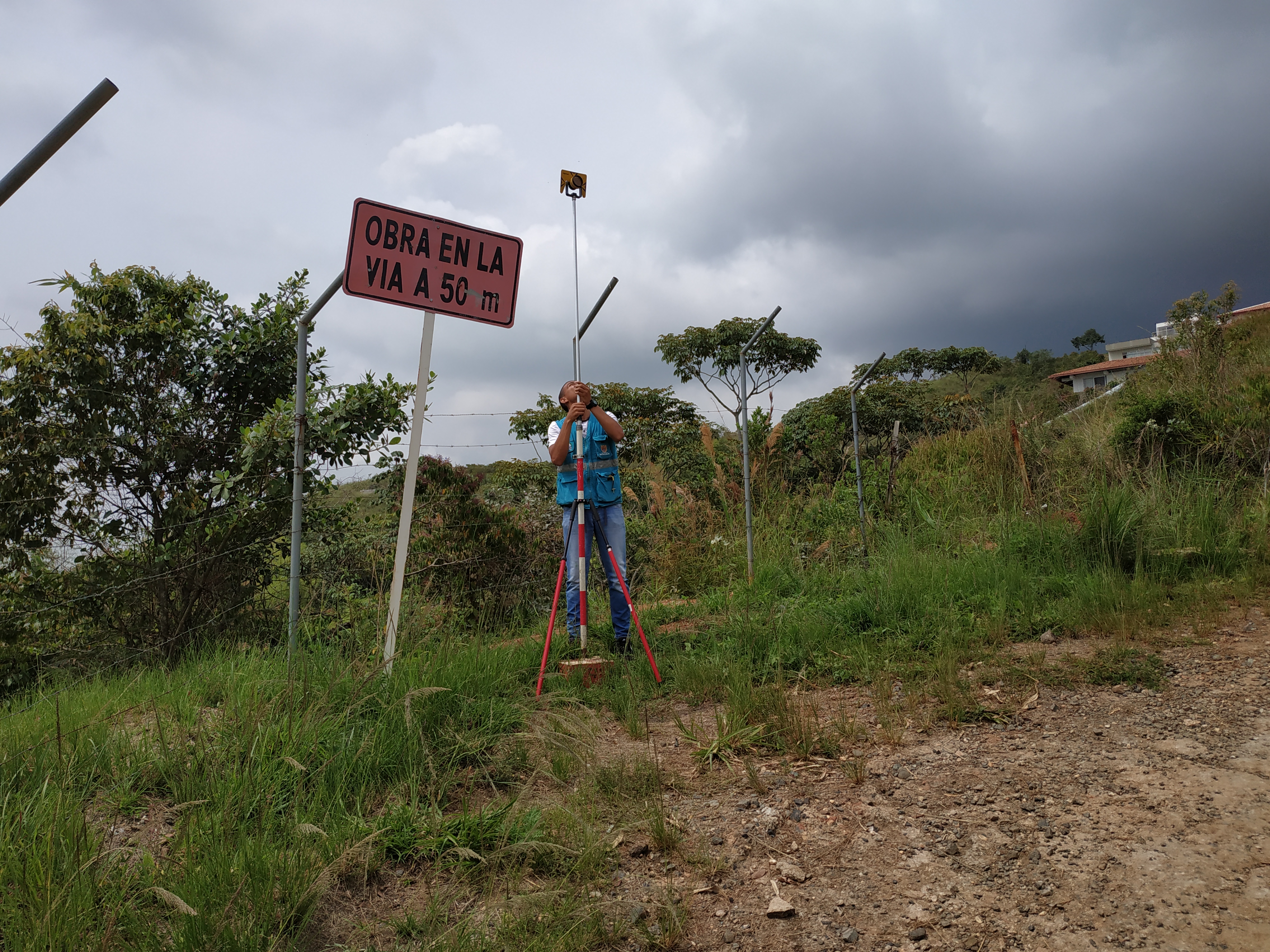 Persona ubicada en un referente geodésico con equipos de medición en la zona rural de Cali.