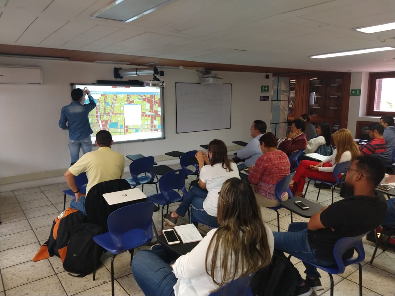 Asistentes atendiendo las explicaciones del personal técnico de la IDESC sobre el mapa interactivo de uso del suelo.